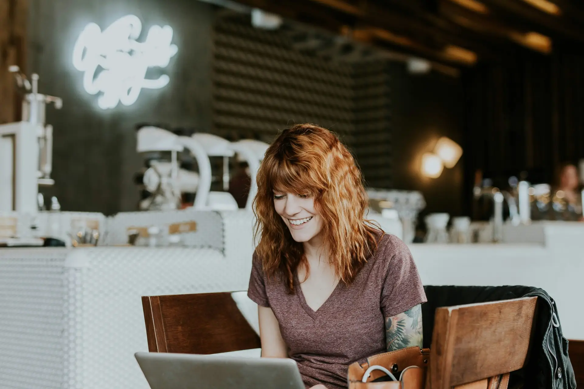 Woman engaging with short-form video marketing content on her laptop in a cafe.